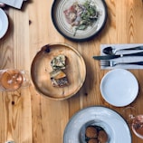 A rustic wooden table set with fresh seafood dishes and wine glasses.