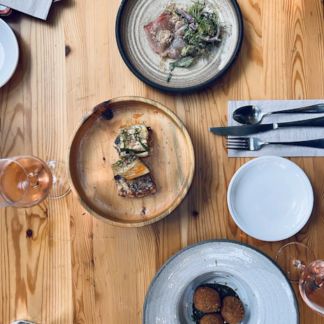 An overhead shot of a wooden table set with a variety of dishes and beverages, ready to be shared.