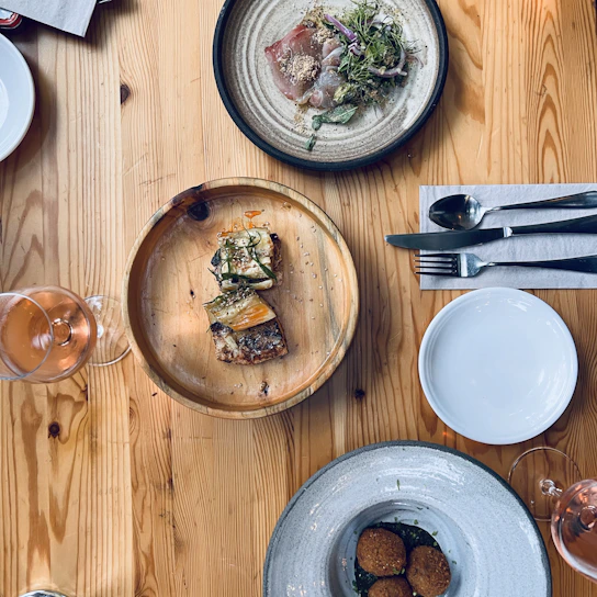 Close-up of a rustic wooden table set with vibrant, freshly prepared appetizers under soft natural light.