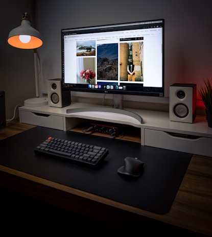 A modern desktop computer setup featuring a large monitor and ergonomic mouse on a clean desk.