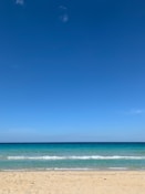 A serene beach scene with crystal clear turquoise waters and gentle waves.