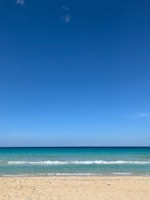 A serene beach with turquoise waves under a clear blue sky, evoking calm and trust.