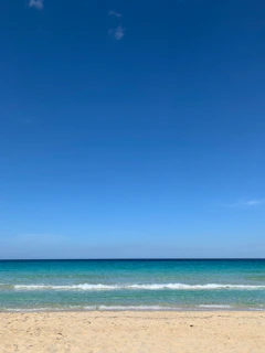 A panoramic beach scene with turquoise waves gently lapping against golden sand.