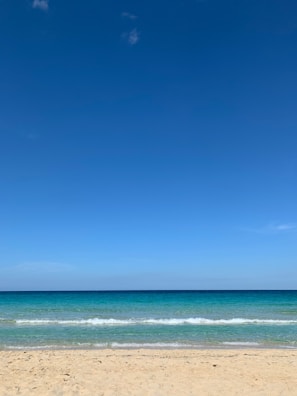 A peaceful beach scene with turquoise waves gently lapping against smooth white sand.