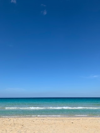 A serene beach scene with soft waves under a clear blue sky, evoking calm and clarity.