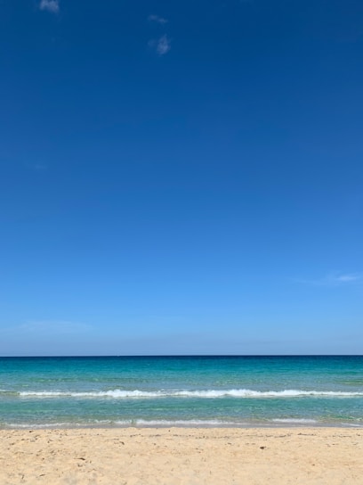 A vibrant beach scene with turquoise waves gently lapping the shore under a bright, clear sky.