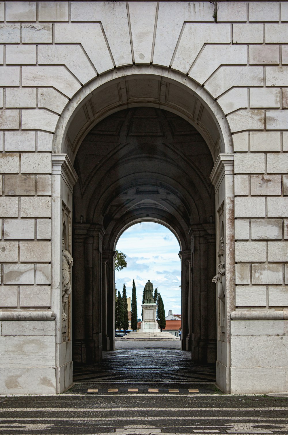 a stone archway with a street and trees in the background