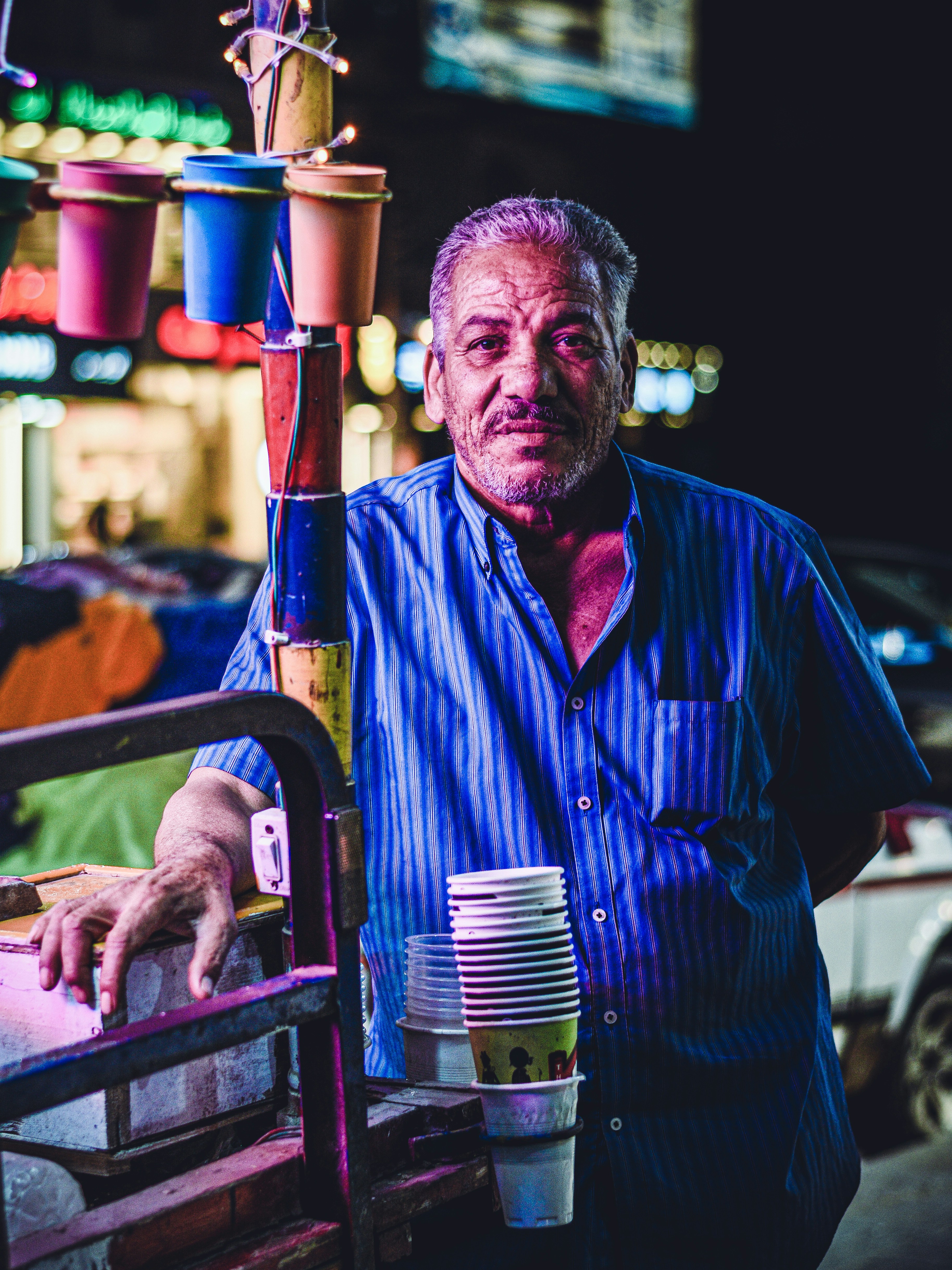 a man with purple hair and a beard holding a stack of beer cans