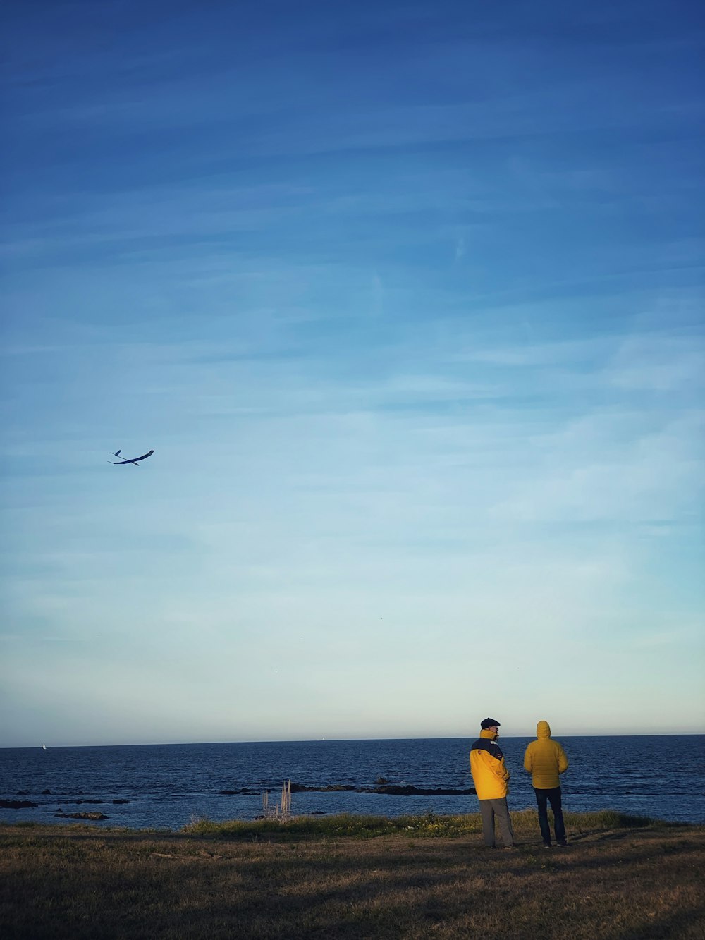 a couple of people stand near each other on a beach