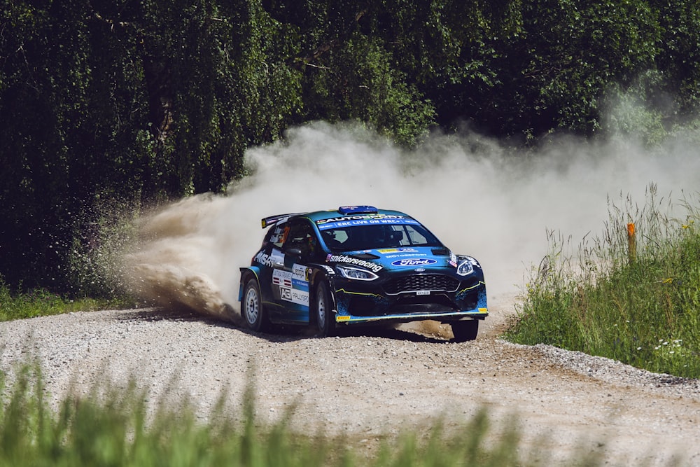 a blue car driving on a dirt road with smoke coming out of it