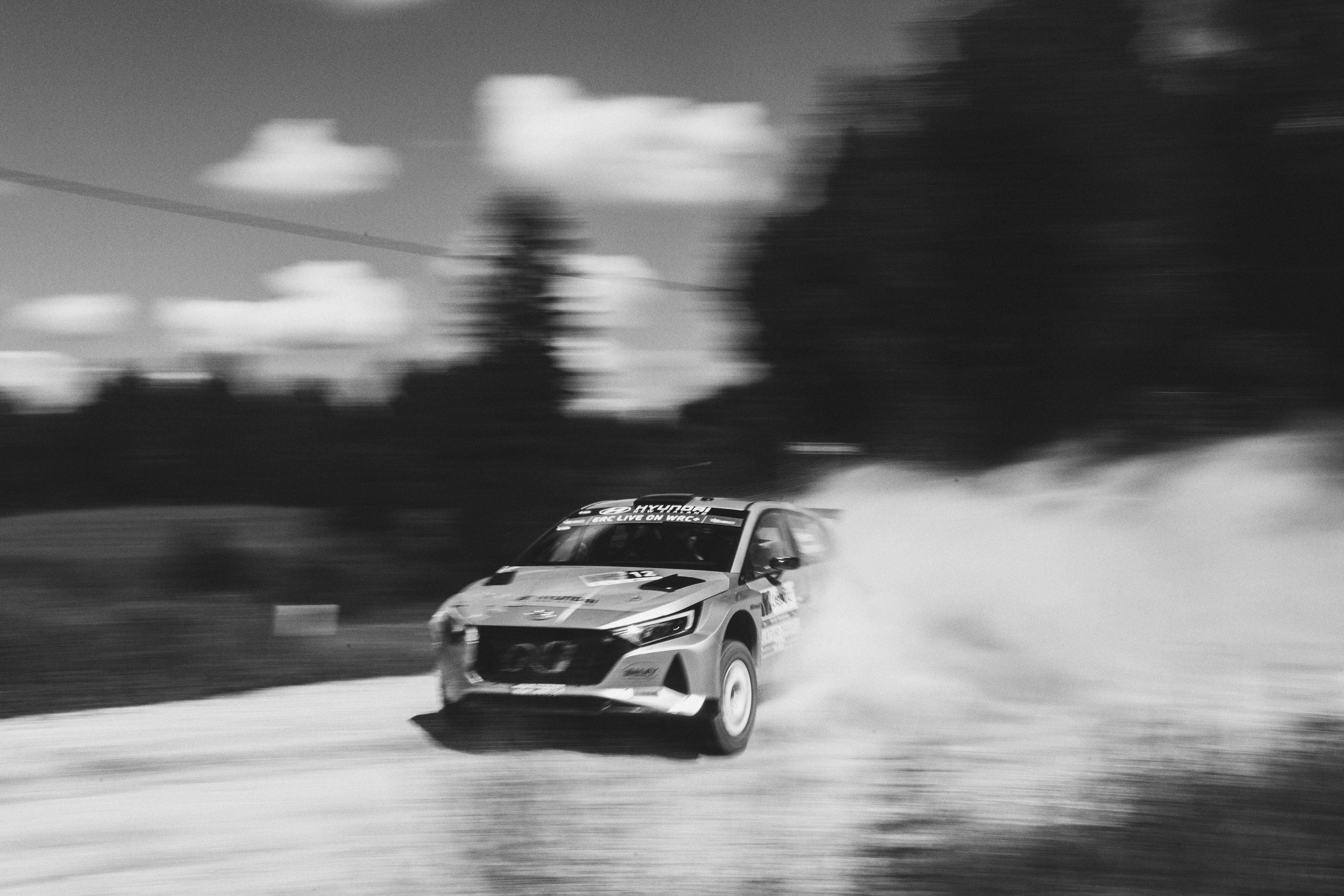 A close shot of a car tire kicking up dust on a gravel road during a rally race.