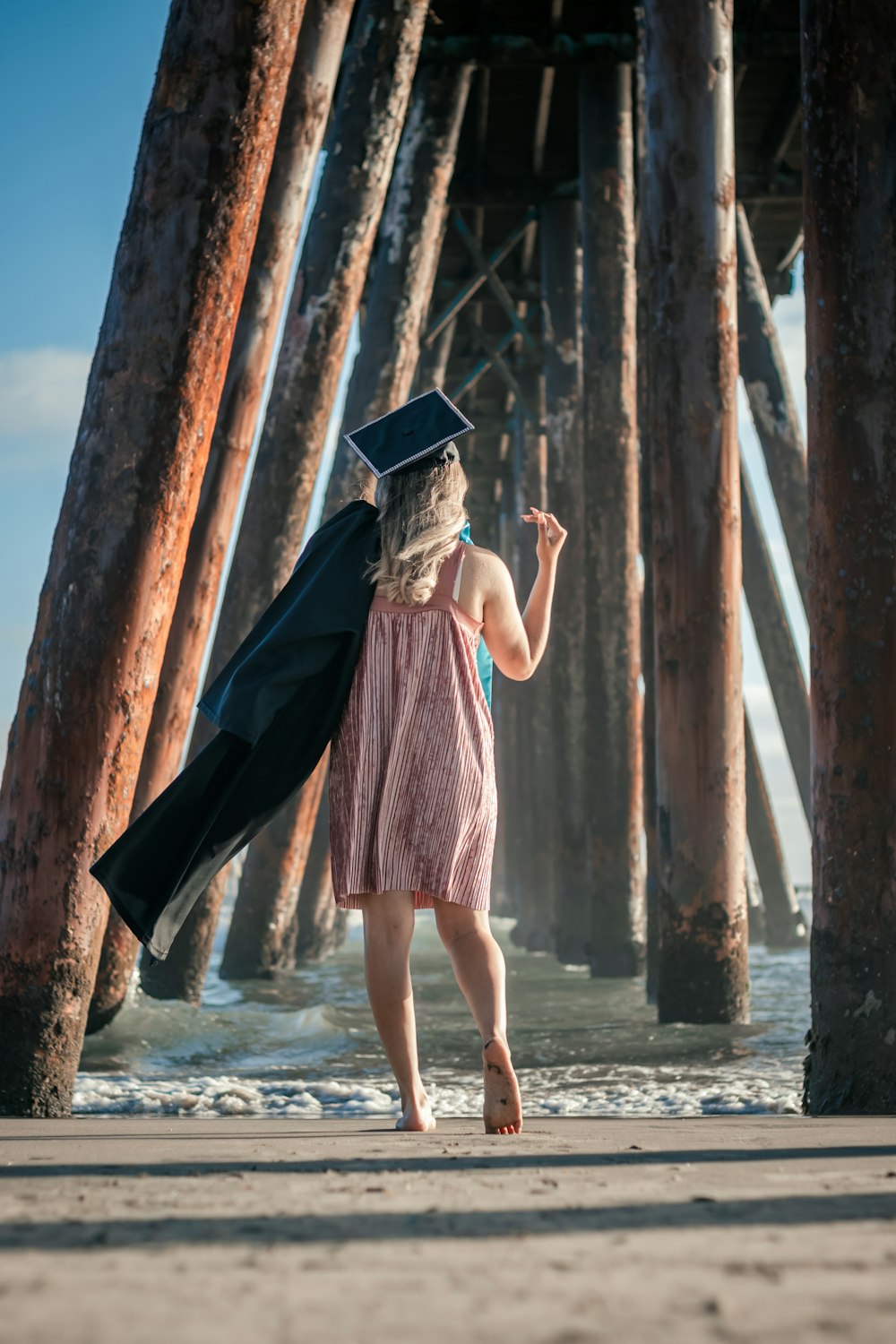 a person holding a hat and walking on a beach