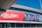 Large building facade featuring a prominent red Rakuten advertisement next to an image of six soccer players in team uniforms. The facade includes the slogan 'The Big Picture: Making history together'.