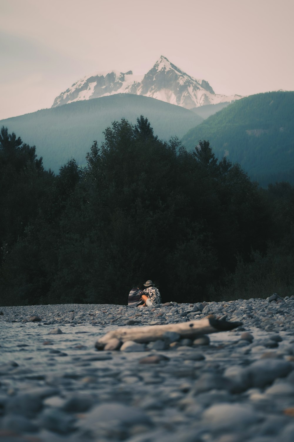 a person sitting on a rock in front of a mountain