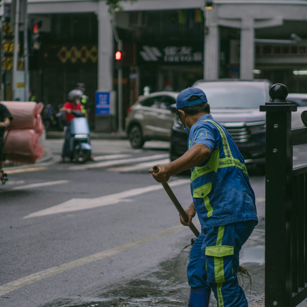 a person in a safety vest holding a broom on a street