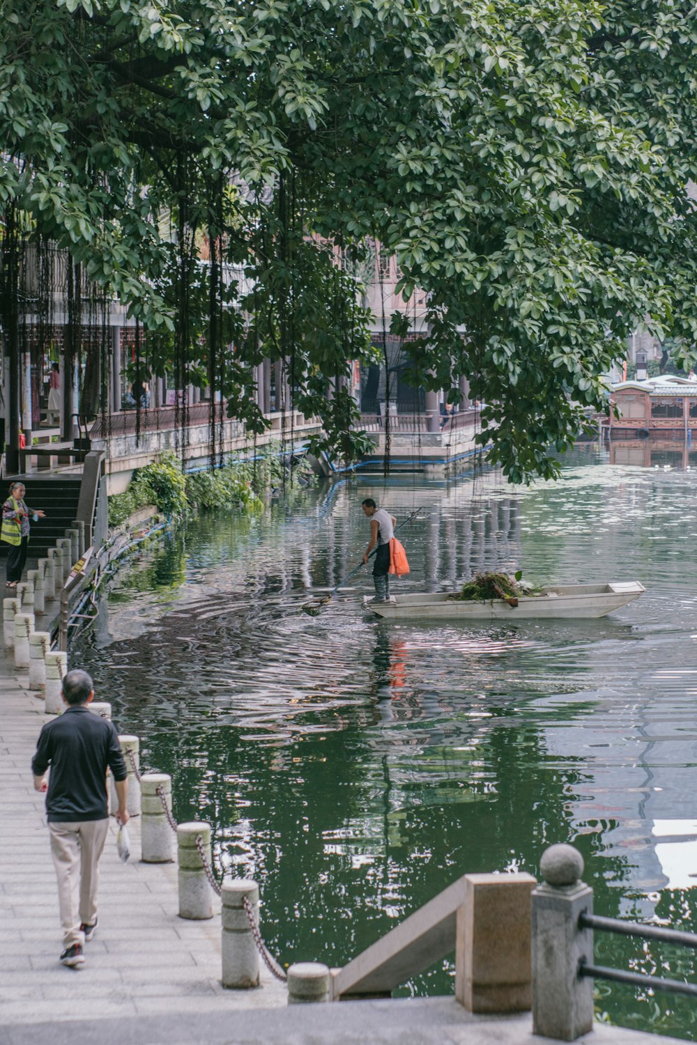 people walking on a sidewalk next to a body of water