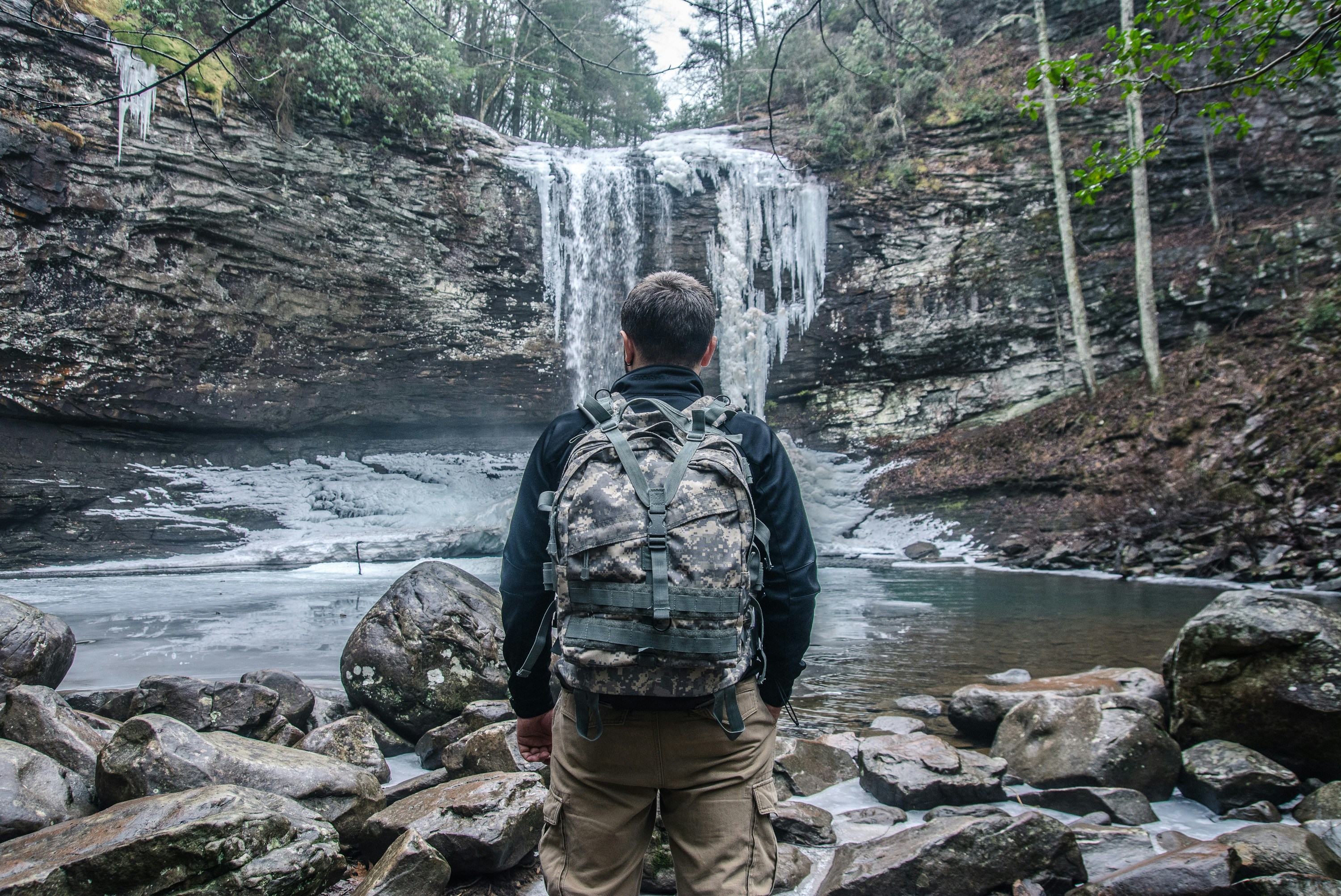 a man standing in front of a waterfall