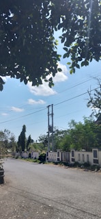 Sunlit plot with boundary walls and a paved road in a peaceful Pune locality.