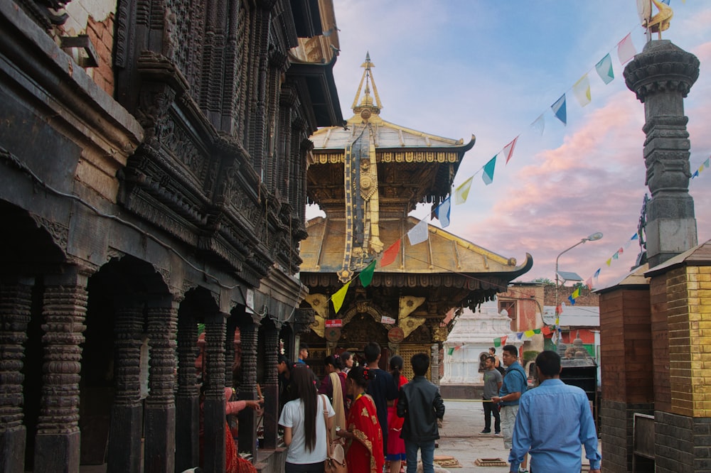 a group of people walking on a street with buildings and a colorful sky