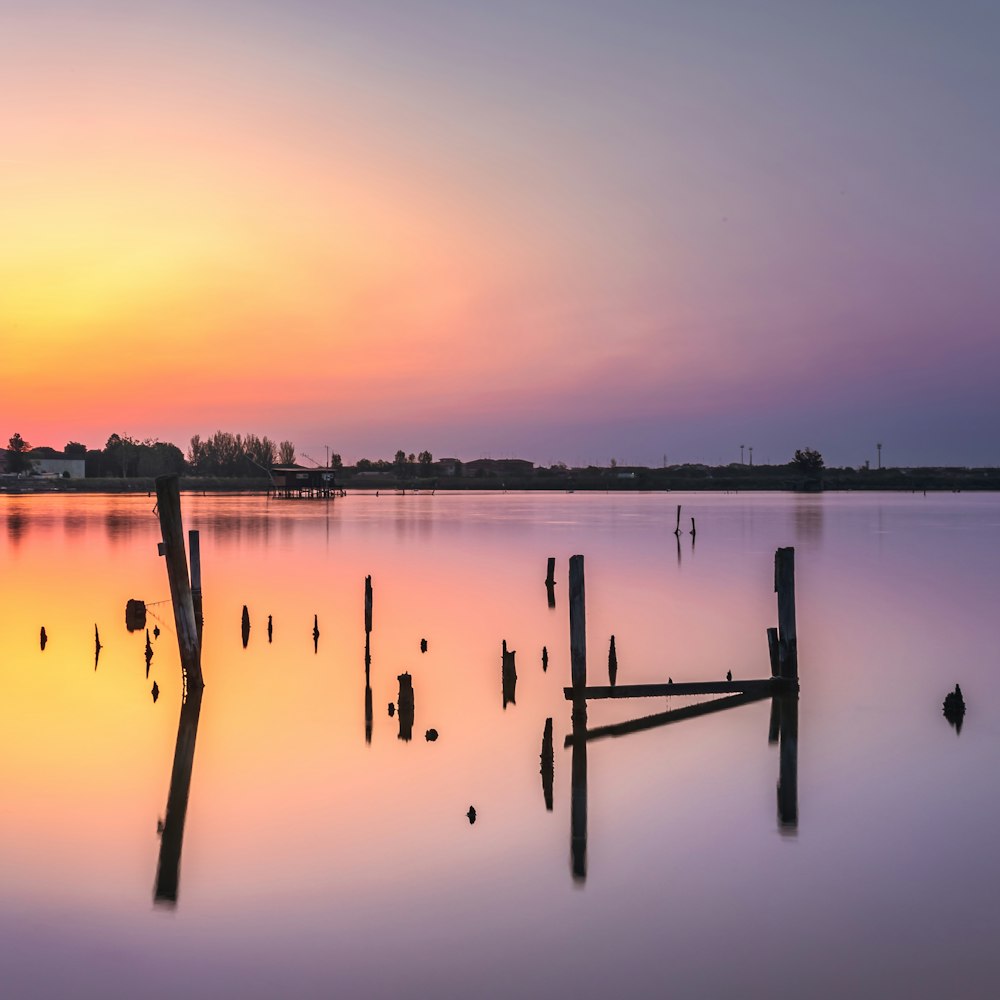 a body of water with trees and a sunset in the background