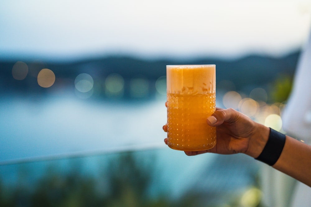 a hand holding a glass of orange juice