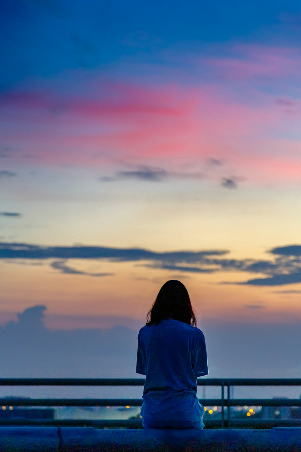 a person sitting on a balcony looking at the sunset