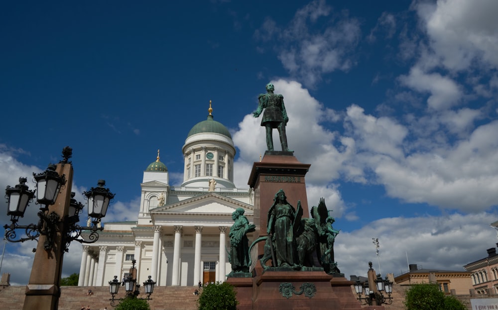 a statue in front of a white building with columns and a dome