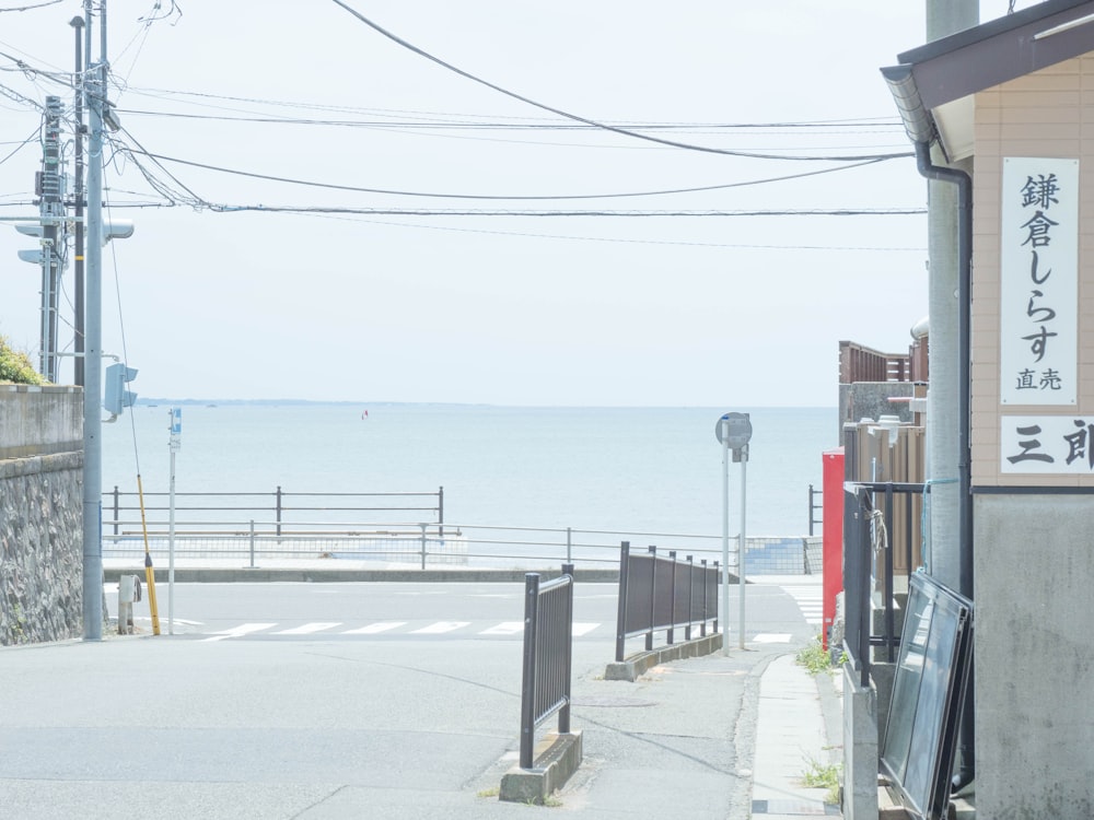 a street with a fence and a body of water in the background