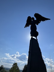 A guardian angel soaring above a peaceful countryside at sunrise.