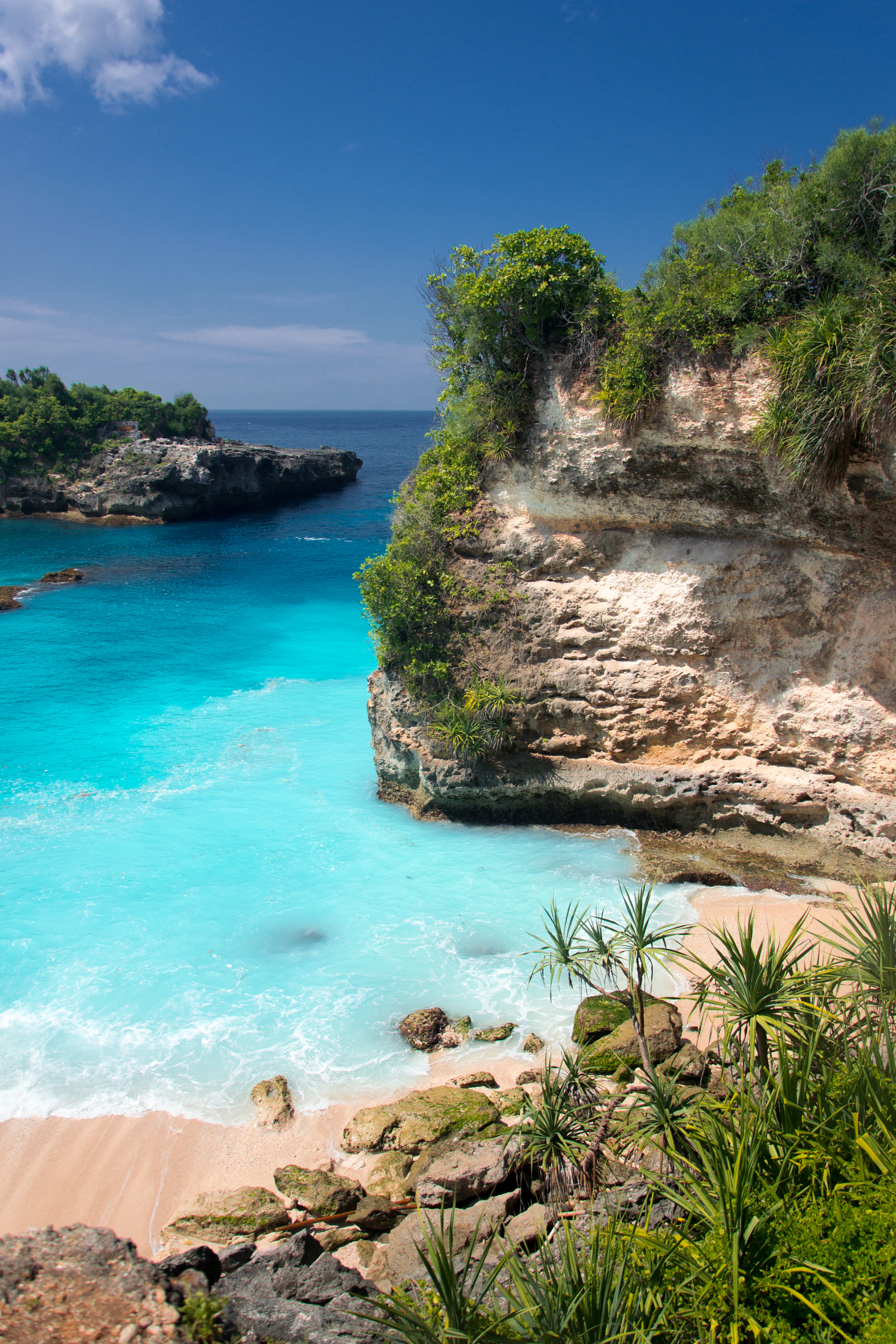 Mar azul-turquesa em uma enseada cercada por falésias e vegetação em Bali