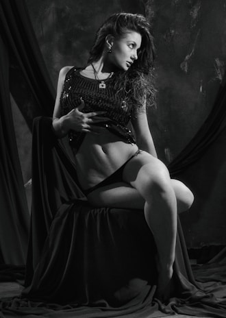 A softly lit boudoir portrait featuring a model draped in warm nude silk, set against an obsidian black backdrop.