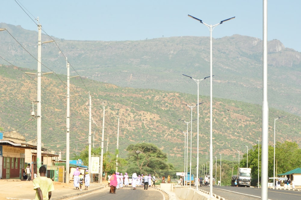 a group of people walking on a road with tall white poles