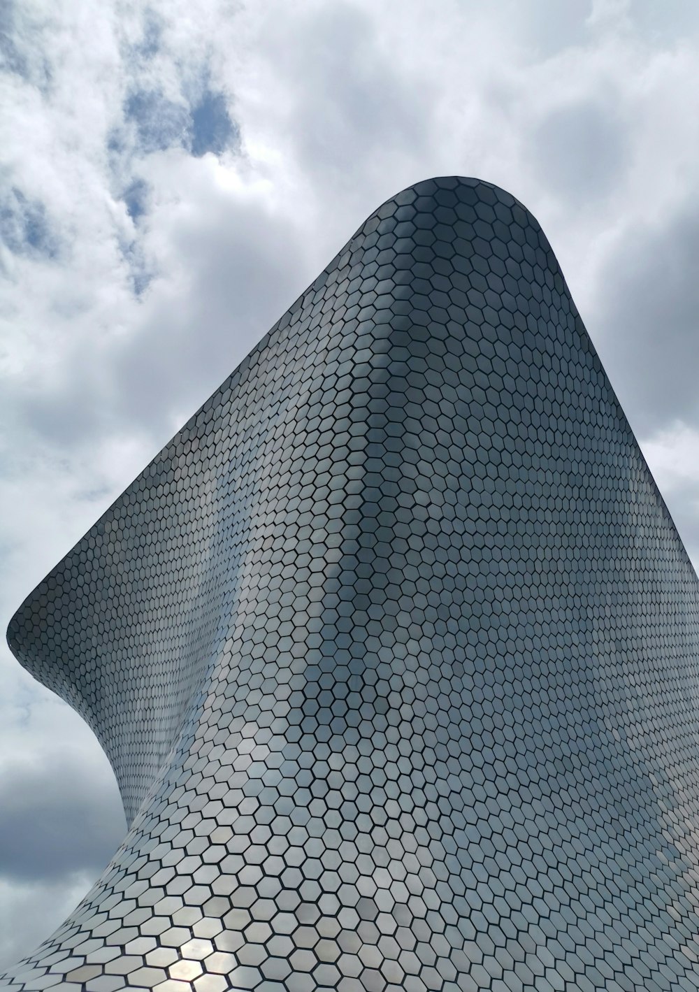 a tall building with clouds in the background with Museo Soumaya in the background