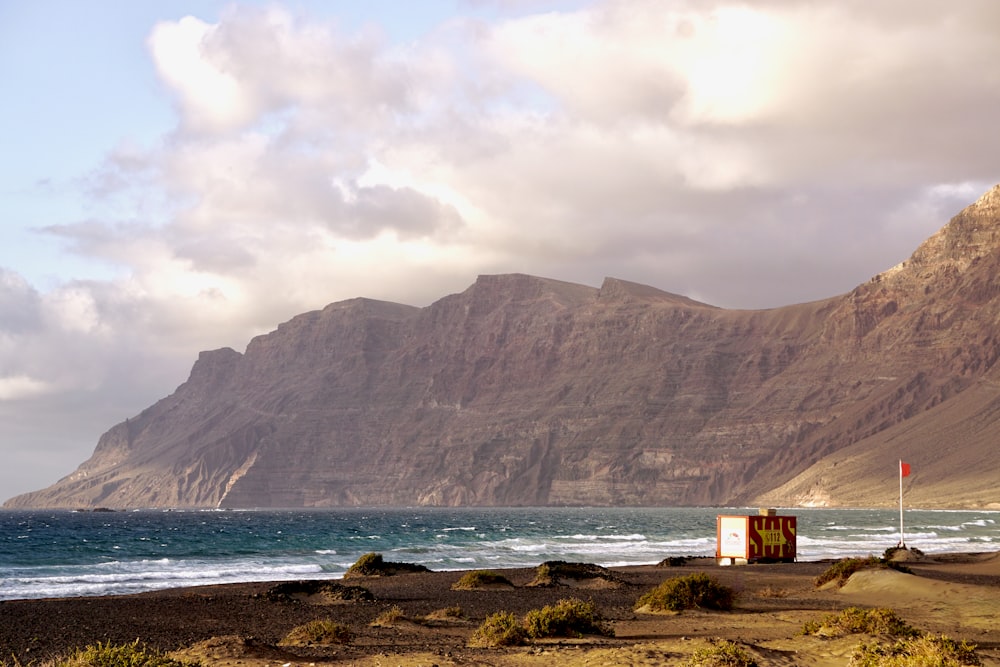 a beach with a sign and mountains in the background