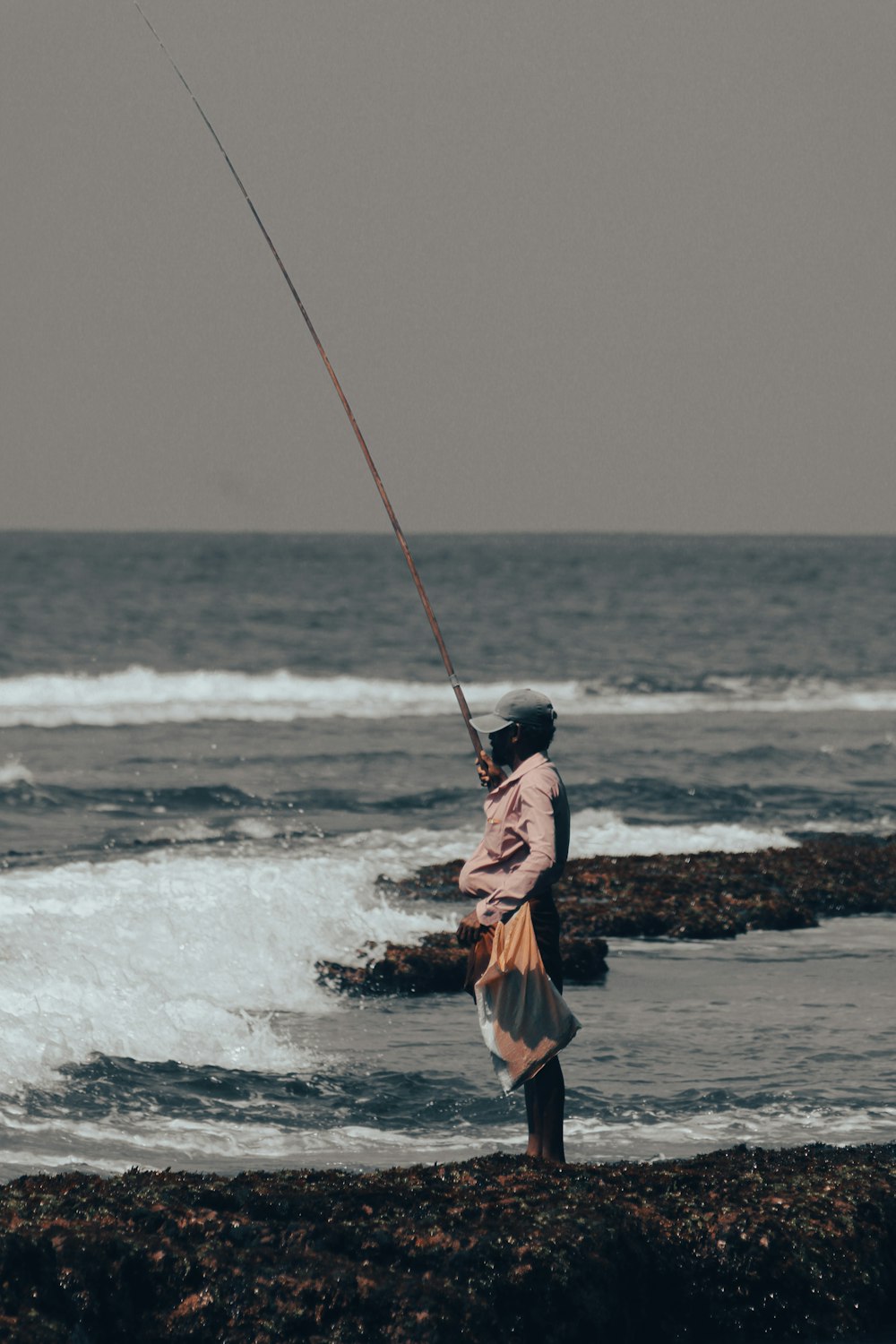 a person holding a fishing pole on a beach