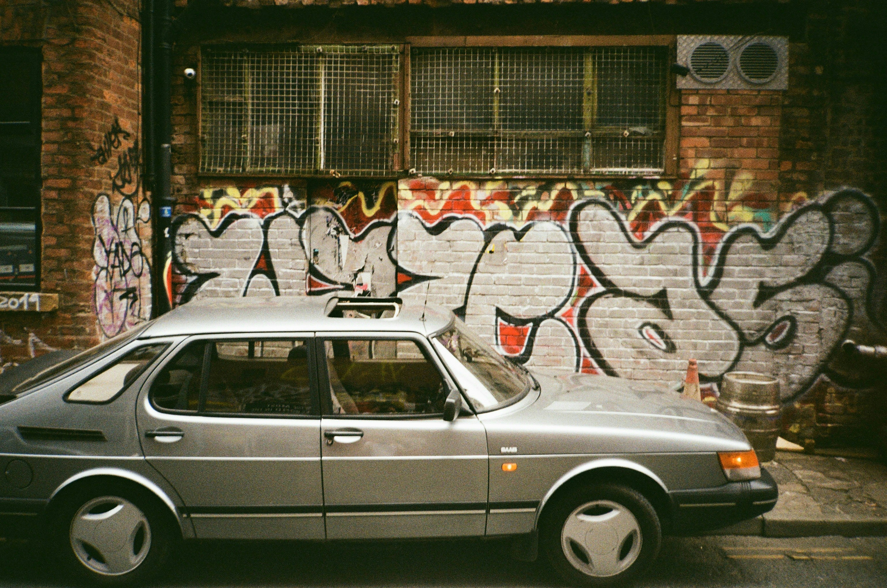 a car parked in front of a wall covered in graffiti