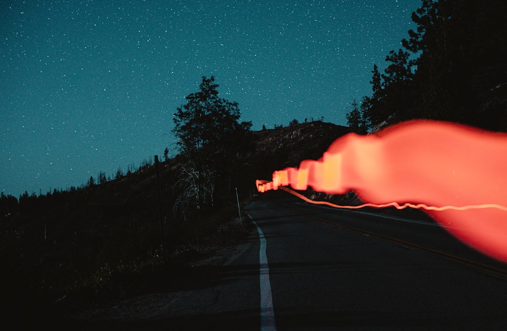 a road with a fire on the side and trees on the side