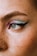 A close-up of the left eye area with detailed makeup featuring a blend of pastel blue and pink eyeshadow, accentuated by a bold black winged eyeliner. The skin is fair with visible freckles, and there is a small nose piercing on the side.
