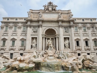 a large building with statues and a fountain in front of it with Trevi Fountain in the background
