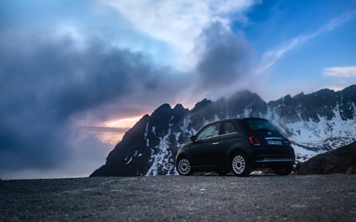 A cozy rental car parked beside a scenic mountain road at sunset, ready for adventure.