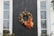 A cozy front door adorned with a vibrant autumn leaf wreath glowing in warm natural light.