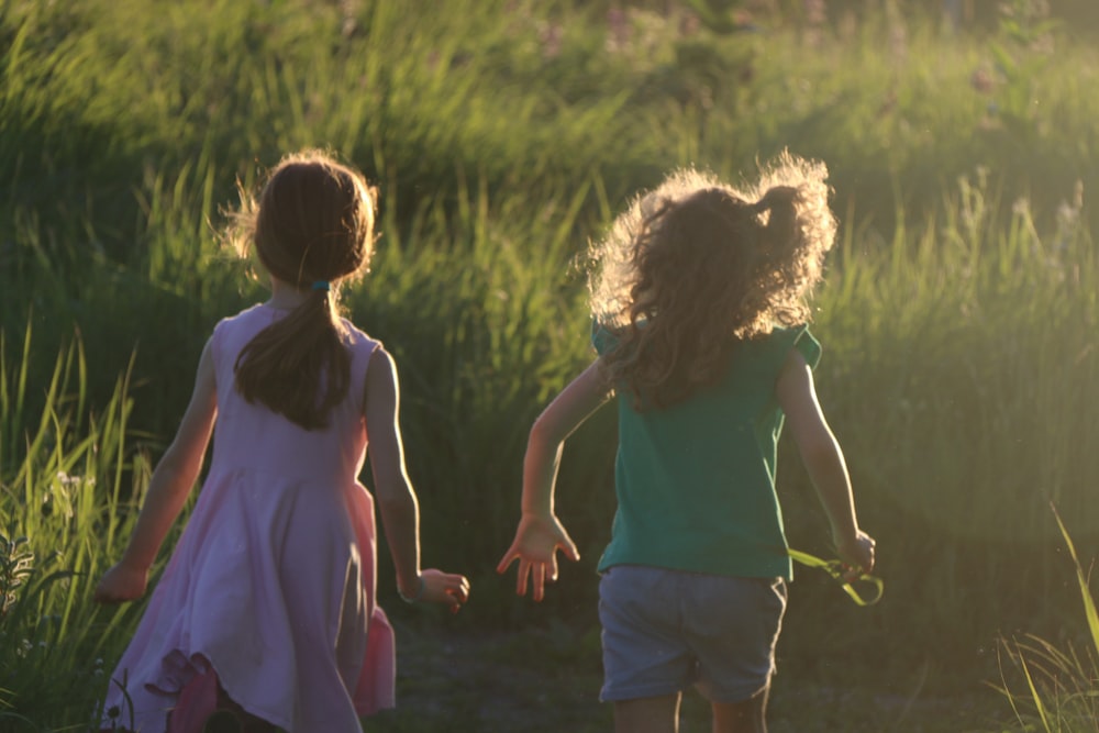 a couple of girls walking in a field with a bear