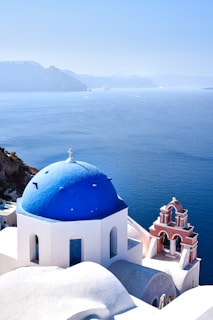 a white building with a blue roof by a body of water