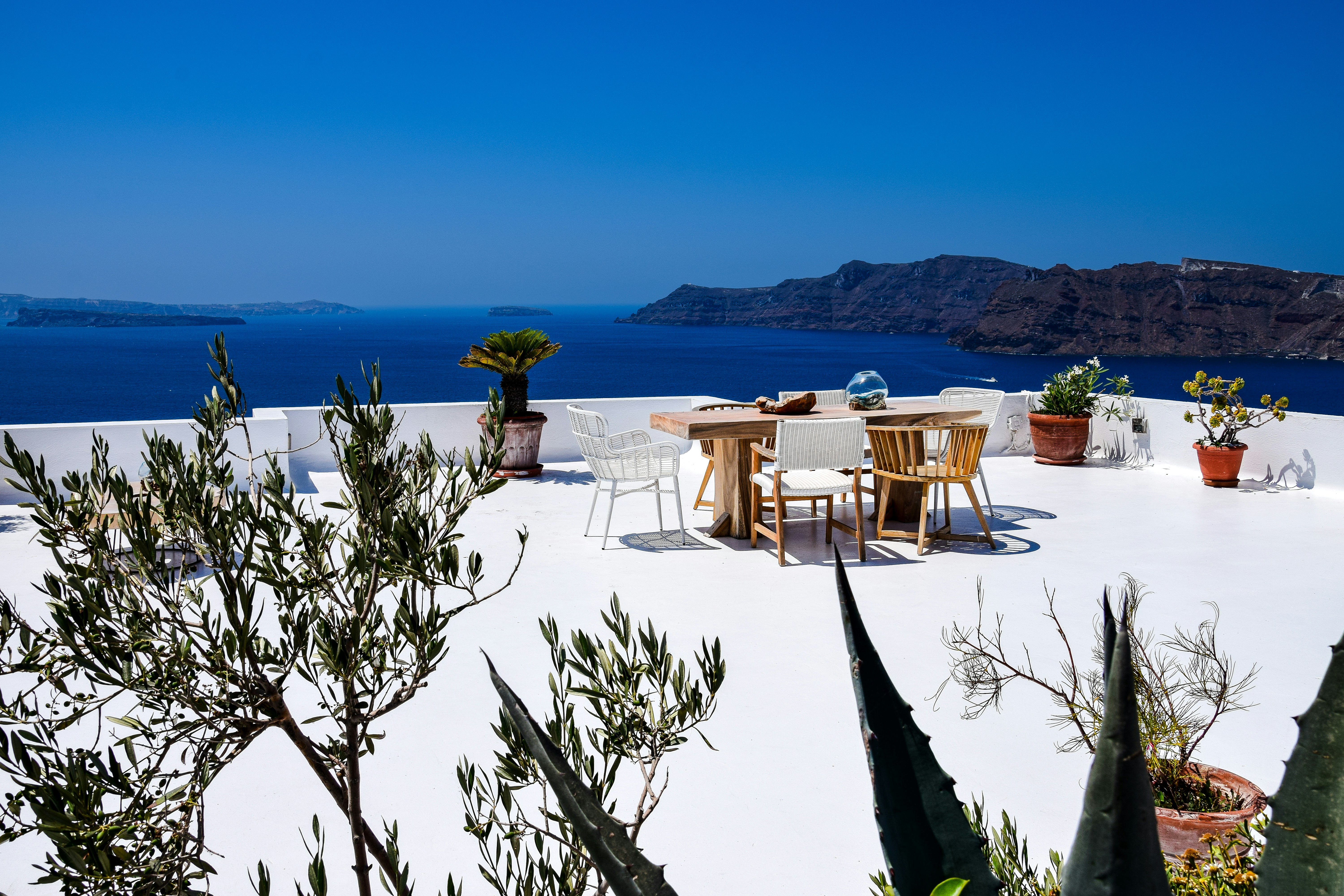 a table and chairs on a beach, Santorini, Greece.