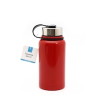 A red insulated bottle with a stainless steel cap and a black strap. Attached is a white tag with a blue accent that reads 'Squeeze 600 ml'. The bottle is set against a plain white background.