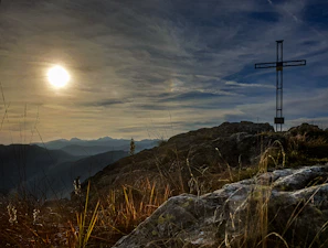 A dramatic sunset behind an ancient cross on a hill