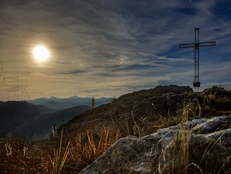 A dramatic sunset behind an ancient cross on a hill