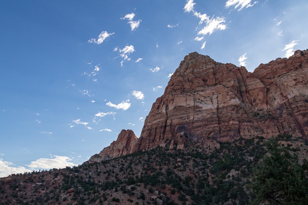 a rocky mountain with blue sky and clouds