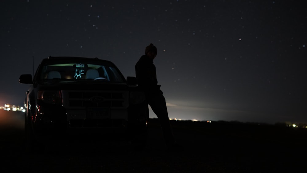 a man standing next to a car at night