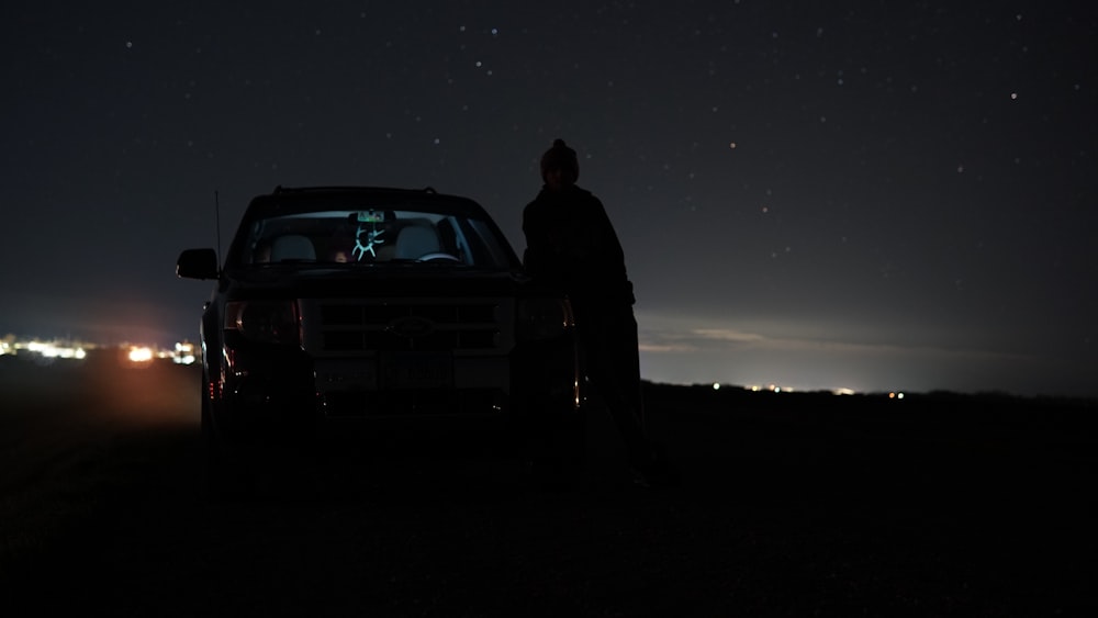 a man standing next to a car at night